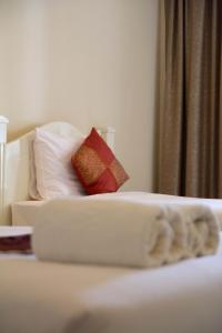 a white bed with two red pillows on it at Grandsmile Wellness Resort in Pattaya Central