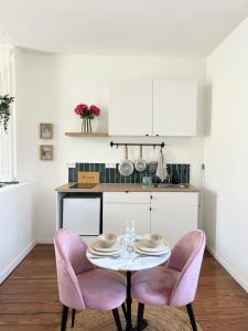 eine Küche mit einem Tisch und zwei rosa Stühlen in der Unterkunft Les Loges des Coteaux - Loge 2 - Luxury lodges with jacuzzi in Blaye
