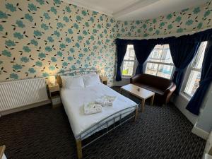 a bedroom with a bed and a chair in it at The Paradise Guest House in Great Yarmouth
