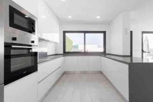 a large kitchen with white cabinets and black appliances at Tequila House - Luxury House in Portugal in Santa Barbara