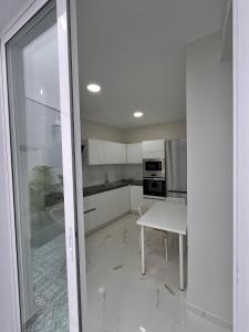 プエルト・デ・ラ・クルスにあるHouse Patio Azul Puerto de la Cruzのテーブルとガラスのドアが付いた白いキッチン +7枚の写真