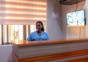a woman sitting at a counter in a room at Natra Apartments Entebbe in Entebbe