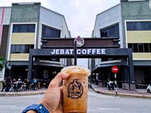a person holding a cup of coffee in front of a building at CASA ADELIA GUESTHOUSE 3b in Cukai +3 photos