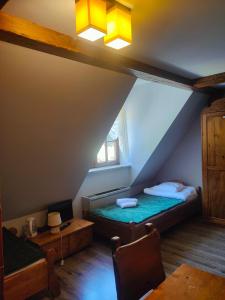 a attic room with a bed and a window at Karczma Parchatka in Kazimierz Dolny