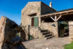 un antico edificio in pietra con porta verde e scale di Magnifique Bergerie AMORE vue panoramique mer et montagne a Cargèse