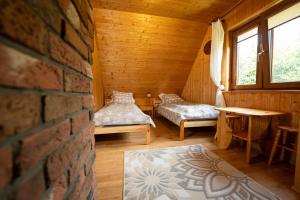 a room with two beds in a wooden cabin at Całoroczne Domki "Stokrotka" in Solina