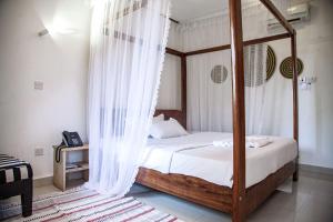 a bedroom with a canopy bed with white curtains at Explorers Hub in Kampala