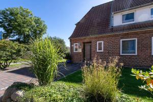 a brick house with a yard with bushes at Ferienwohnung Nordfriesland in Niebüll