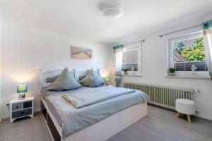 a white bedroom with a bed and two windows at Ferienwohnung Nordfriesland in Niebüll