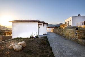 a white building with a stone wall next to a sidewalk at Melissaotelgokceada in Gokceada Town