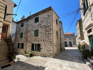 un antiguo edificio de piedra con persianas verdes en una calle en Apartment Mirakul, en Šibenik