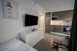 a living room with a television and a kitchen at Brand new studio apartment near the harbour in Turku