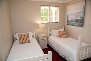 Dos camas blancas en una habitación con ventana. en Sunset Kiss, en Knysna 53 fotos más