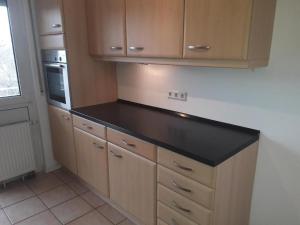 a kitchen with a black counter top and wooden cabinets at City Apartment in Eppelheim in Eppelheim +6 photos