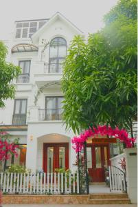 a white house with a white fence and pink flowers at TH Villa, Vinhome Ocean Park, Hanoi in Hanoi
