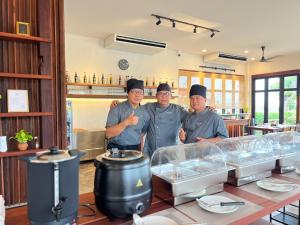 three men standing behind a counter in a restaurant at Zenery Lake Resort in Ban Don Klang