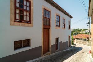a white building with a brown door on a street at Casa do Mestrinho 2 in Avintes