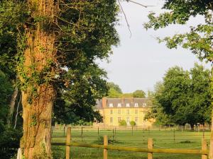 a fence in front of a yellow house with a tree at Hotel Les Lodges de Vaugrigneuse in Vaugrigneuse
