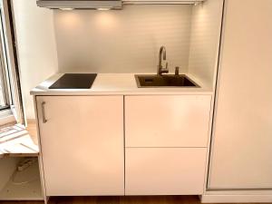 een witte keuken met een wastafel en een aanrecht bij Studio Metro Paris La-defense in Asnières-sur-Seine
