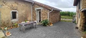 a patio with a table and chairs in front of a building at Au Petit Galop in Nassiet