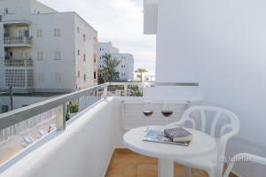 a white table with two glasses of wine on a balcony at Apartamentos Ibiza in Colonia Sant Jordi