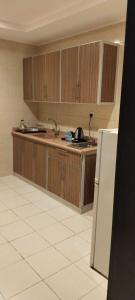 a kitchen with wooden cabinets and a refrigerator at Hmm Serviced Apartments in Al Kura