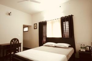 een slaapkamer met een bed met witte lakens en een raam bij Daffodils Inn in Alleppey +22 foto's
