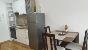 een keuken met een tafel en een roestvrijstalen koelkast bij Apartman NEMANJA in Vrnjačka Banja