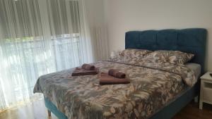 een bed met een blauw hoofdeinde met twee bruine schoenen erop bij Apartman NEMANJA in Vrnjačka Banja +8 foto's