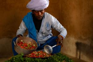 a man with a turban cooking food in a pot at Mhamid Nomad Camp in Mhamid