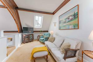 a living room with a white couch and a tv at The Tracery - Norfolk Cottage Agency in Fakenham