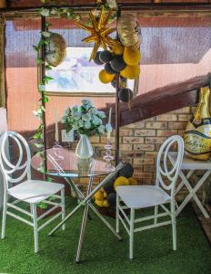 a glass table with two chairs and a table with a vase at Siyaya Sbosh BnB in Reitz