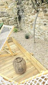 a wooden deck with a basket next to a stone wall at La maison du Pays d'Auge in Troarn
