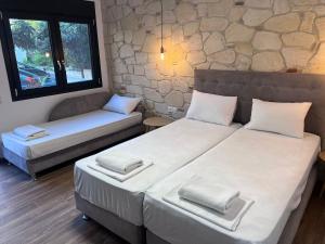 two beds in a room with a stone wall at Naria Studios in Skala Fourkas