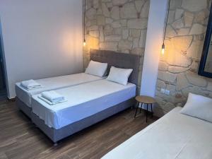 a bedroom with two beds and a stone wall at Naria Studios in Skala Fourkas +11 photos