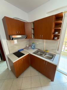 a kitchen with wooden cabinets and a sink at Ridi Apartament's in Vlorë