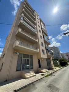 a tall white building with stairs on a street at Ridi Apartament's in Vlorë