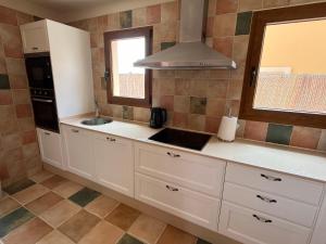 une cuisine avec des armoires blanches, un évier et une fenêtre dans l'établissement Villa Senorio, à Caleta de Fuste 18 autres photos