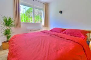 a bedroom with a large red bed with a window at Charmant Studio rénové à Antibes, plage à 10 min à pied in Antibes