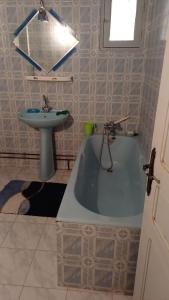 a bathroom with a blue tub and a sink at Dar Al Yasmine in Tabarka