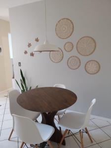 a dining room table and white chairs and a wall at Apartamento Vila do Sol in Blumenau