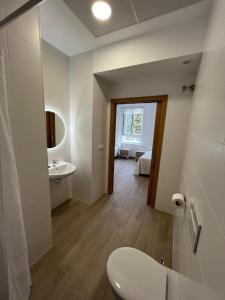 a white bathroom with a toilet and a sink at Apartamentos del Raval in Gandía +30 photos