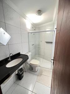 a white bathroom with a toilet and a sink at Pousada Verdes Mares in Maragogi