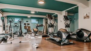 einen Fitnessraum mit mehreren Laufbändern und Heimtrainern in der Unterkunft Parkhotel Nümbrecht in Nümbrecht