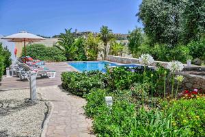 a swimming pool in a garden with chairs and an umbrella at Ta Benna in Għajnsielem