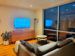 a living room with a couch and a flat screen tv at Adelaide Central Skyline Panoramic Suite in Adelaide