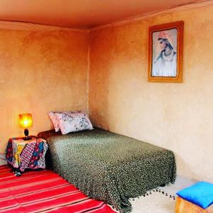 ein Schlafzimmer mit einem Bett und einer Lampe an der Wand in der Unterkunft Ngayan Camp in Marrakesch