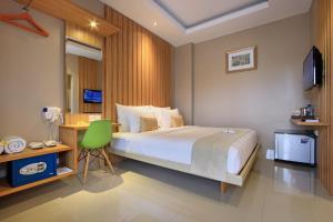 a bedroom with a large bed and a green chair at Puri Padma Hotel in Ubud