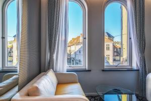ein Wohnzimmer mit einer Couch und drei Fenstern in der Unterkunft Magic Hotel Bergen City Center, a member of Radisson Individuals in Bergen