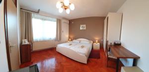 a bedroom with a bed and a desk and a window at Guesthouse Vila in Slunj